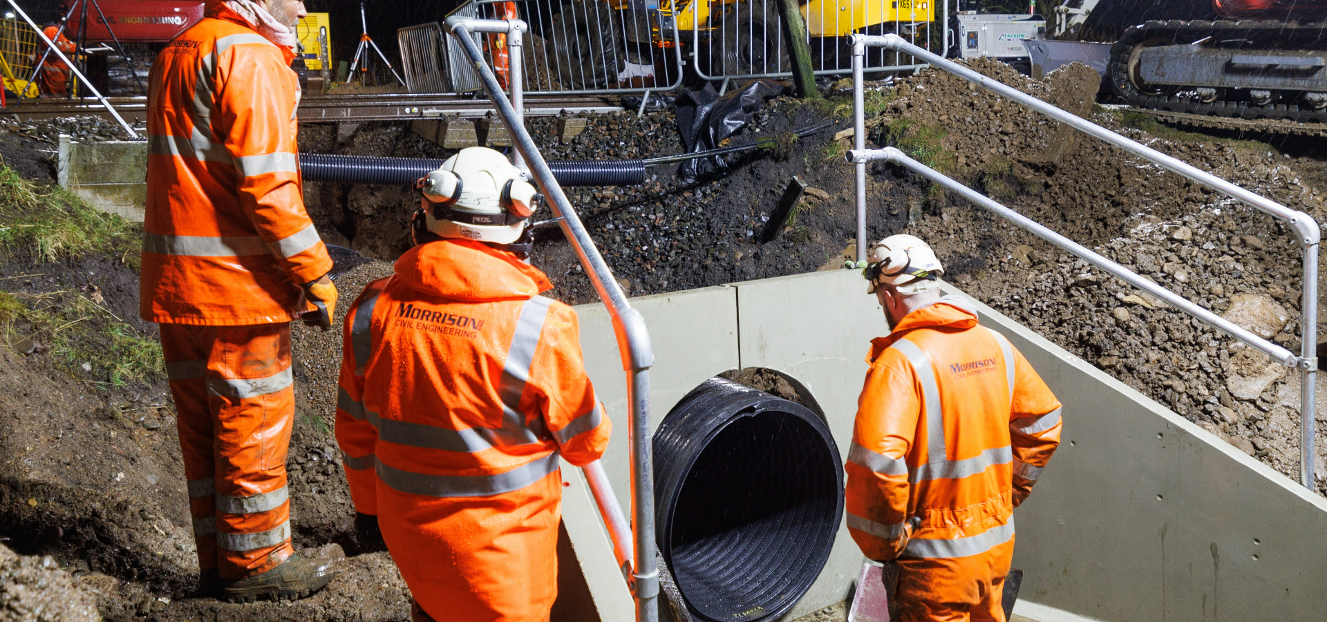 3 men wearing hi-viz looking at pipe