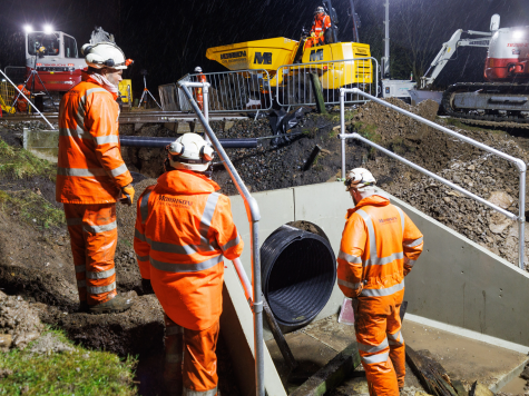 3 men wearing hi-viz looking at pipe